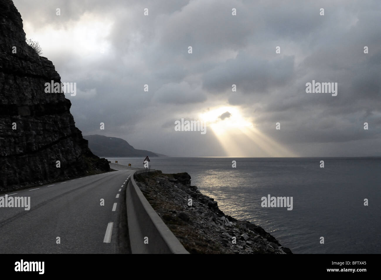 Un vuoto che la strada per Capo Nord. Il sole è splendenti attraverso le nuvole pesanti come se Dio è in cerca di me lì in piedi al di sotto Foto Stock