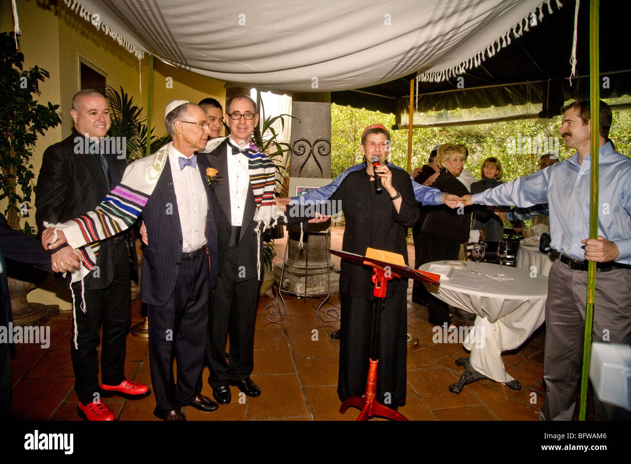 Avvolto in uno scialle rituale un tenendo le mani con la festa di nozze, due uomini gay sono sposati in una riforma cerimonia ebraica Foto Stock