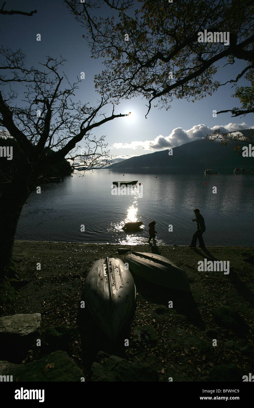 Area di Loch Lomond, Scozia. Vista profilarsi di una figlia della madre e cane sguazzare nell'acqua a Rowardennan rive. Foto Stock