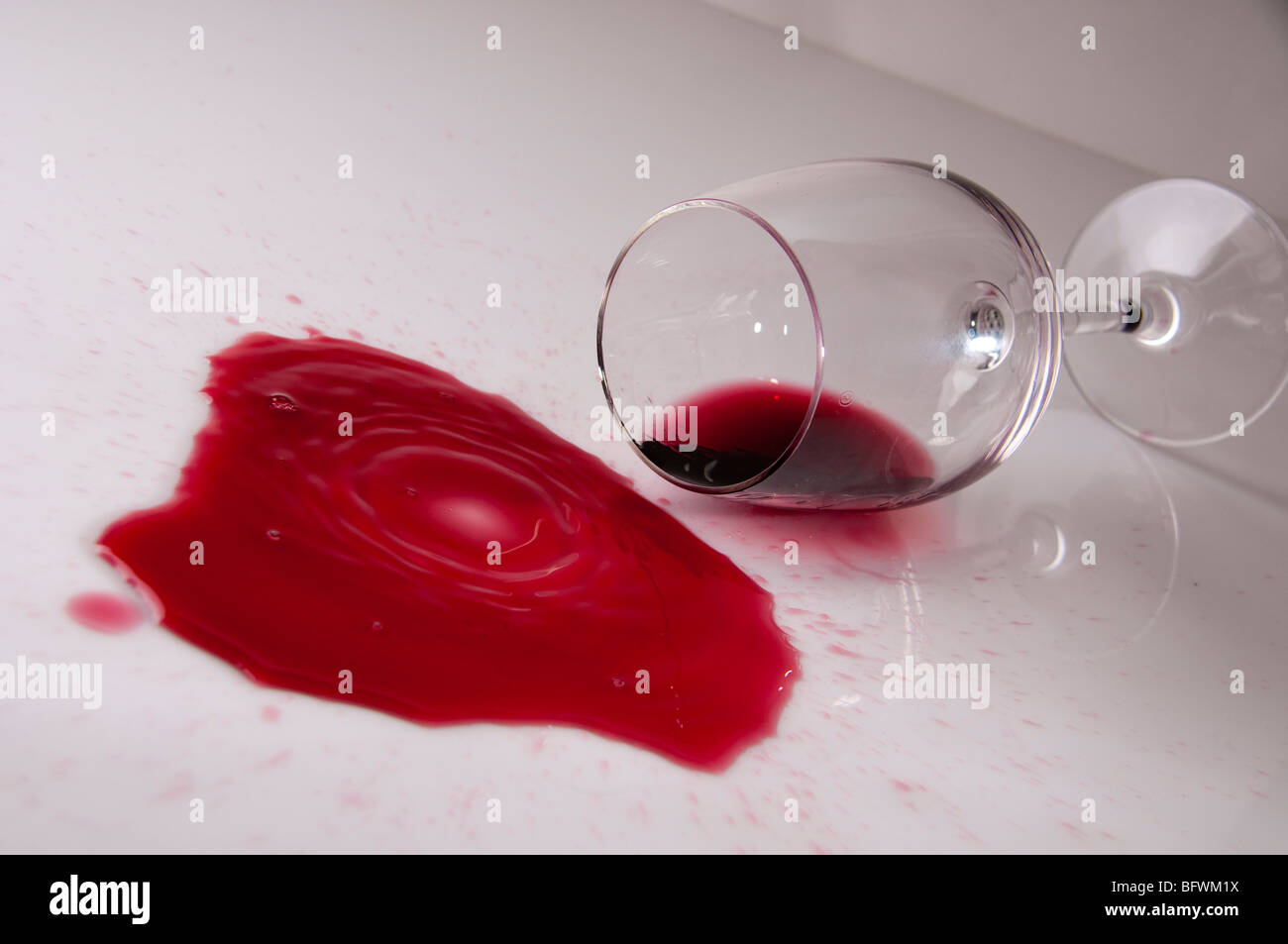 Bicchiere da vino cadde e vino sparsi su tavola con gocce Foto Stock