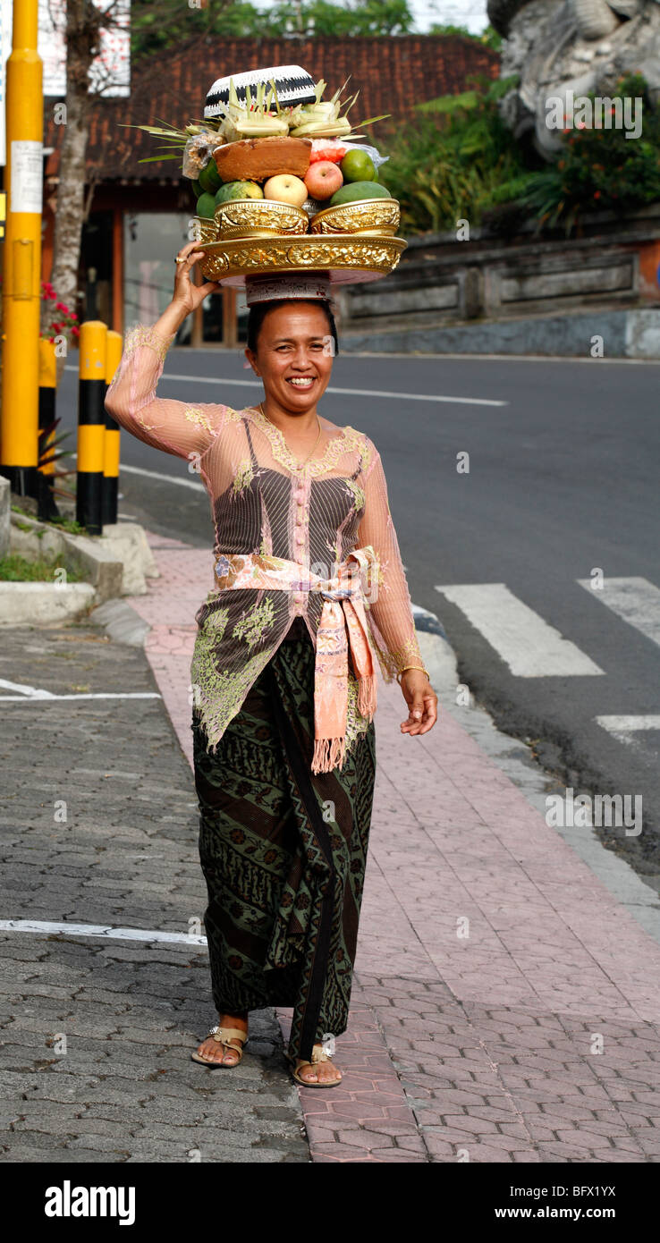 Signora Balinese vestito per il tempio e le offerte di trasporto sul suo capo. Ubud, Bali Foto Stock