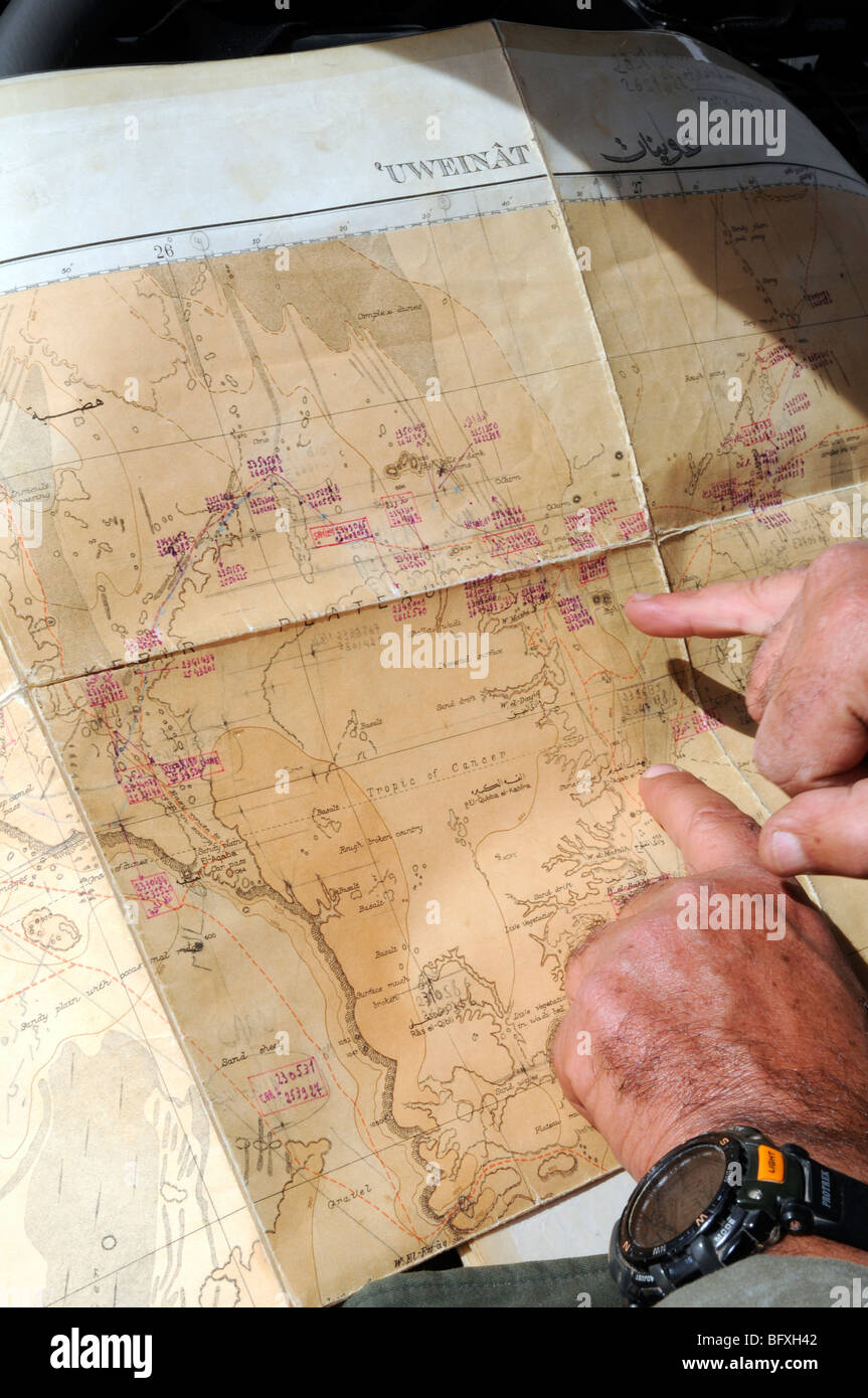 Un safari nel deserto piani leader il suo percorso su una mappa del Gilf Kebir e Jebel Uweinat area del deserto del Sahara, nel Deserto Occidentale Regione in Egitto. Foto Stock