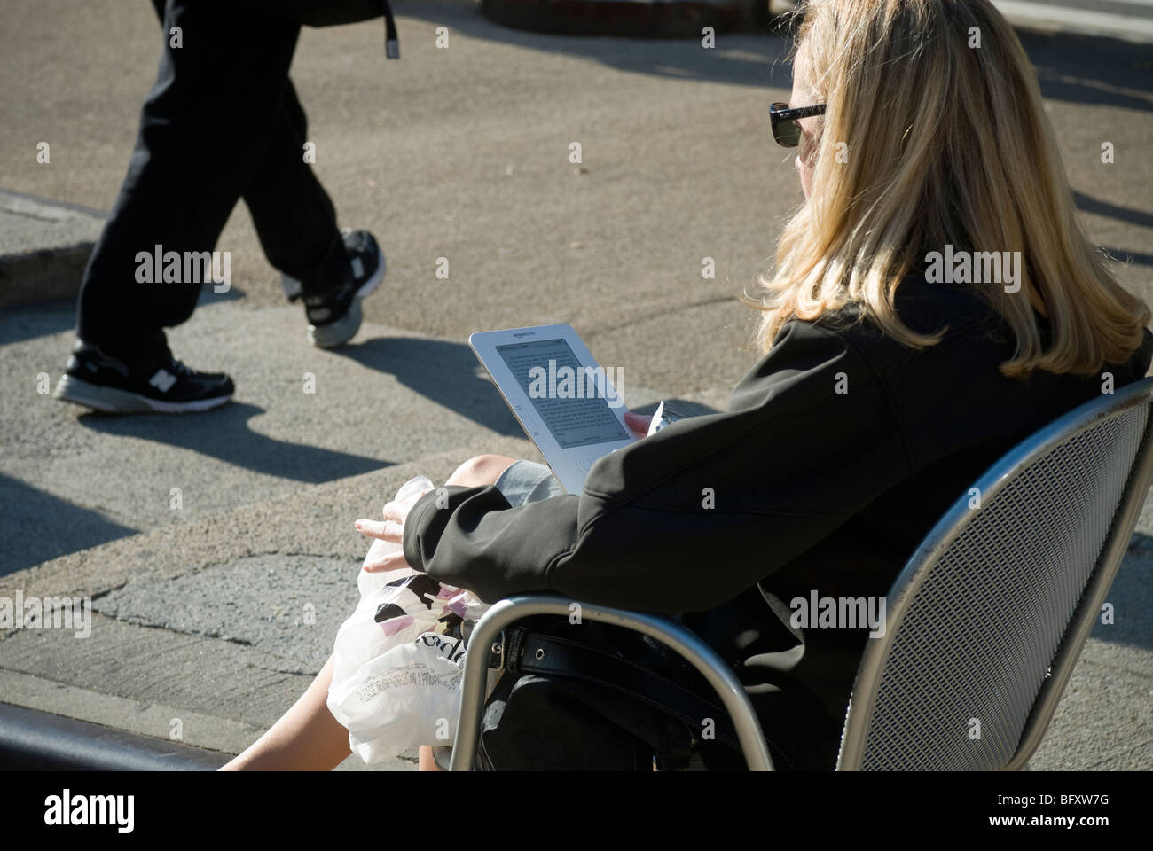 Un lettore utilizza il suo Amazon Kindle libro elettronico sulla strada fuori dal Madison Square Park di New York Foto Stock