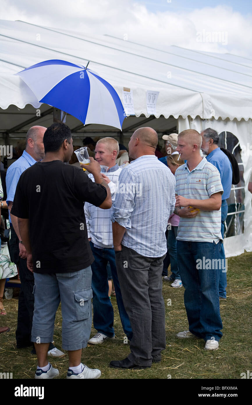 Gruppo di uomini che bevono birra all'aperto in una fiera della contea, Sussex, Inghilterra, Regno Unito Foto Stock