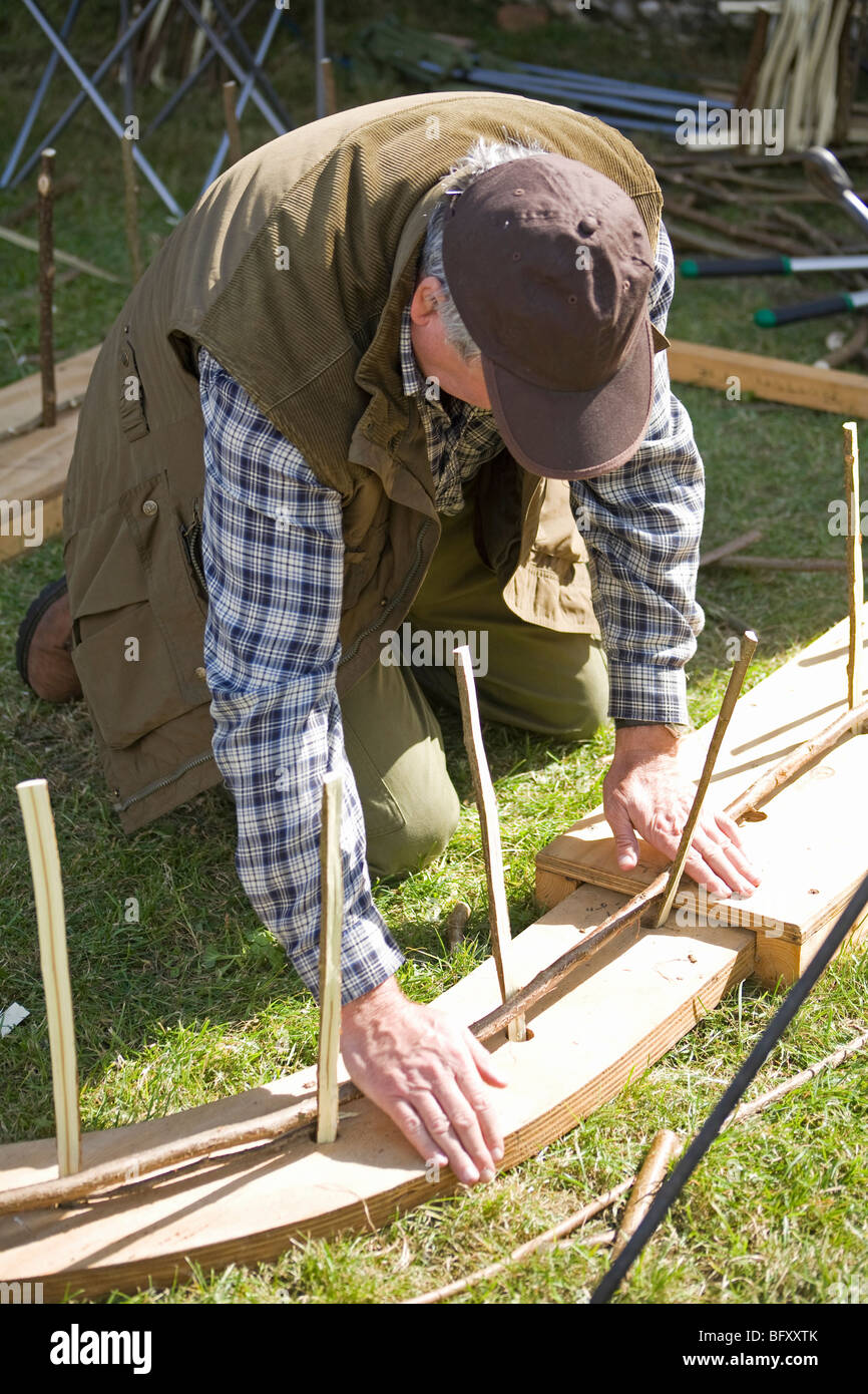 Uomo salice di piegatura attorno ad un telaio. Sussex, Inghilterra Foto Stock