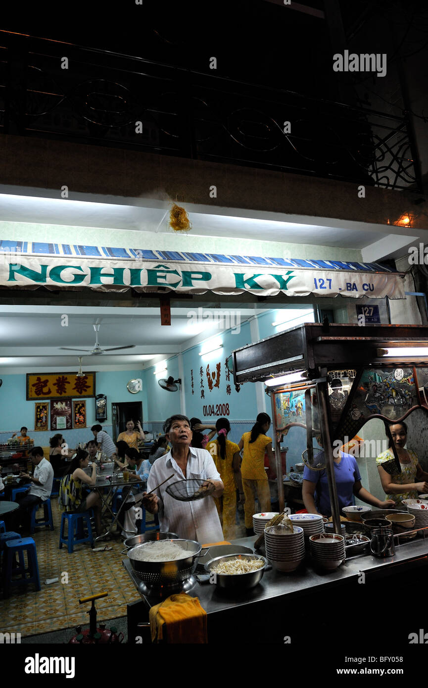 La cottura di tagliatelle all'aria aperta. Un ristorante di cucina si riversa fuori sul marciapiede della Città di Ho Chi Minh (Saigon). Foto Stock