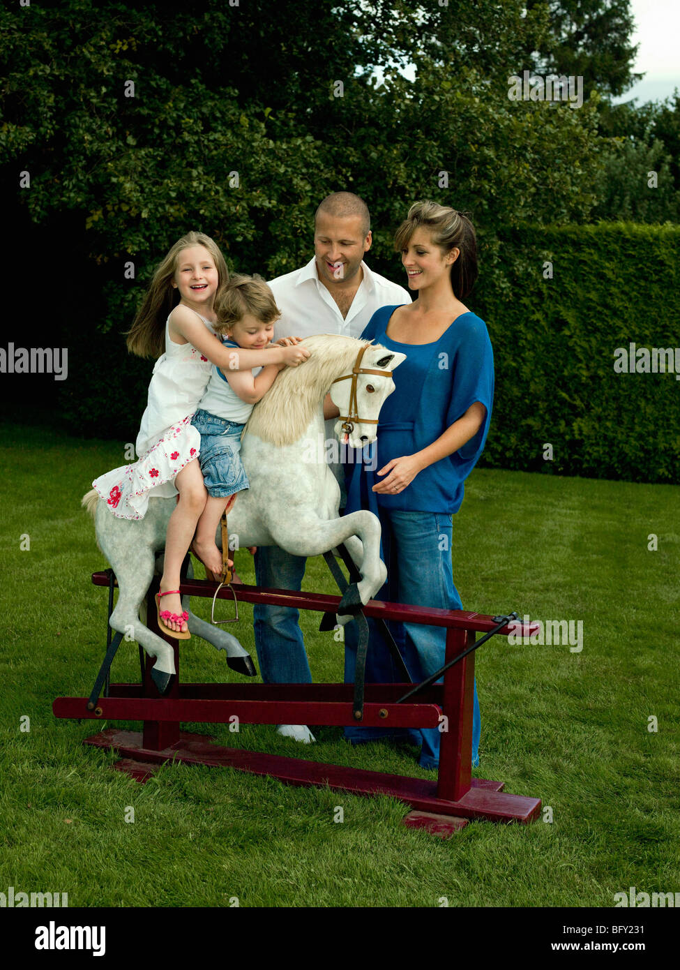 Una famiglia che gioca con un cavallo a dondolo Foto Stock