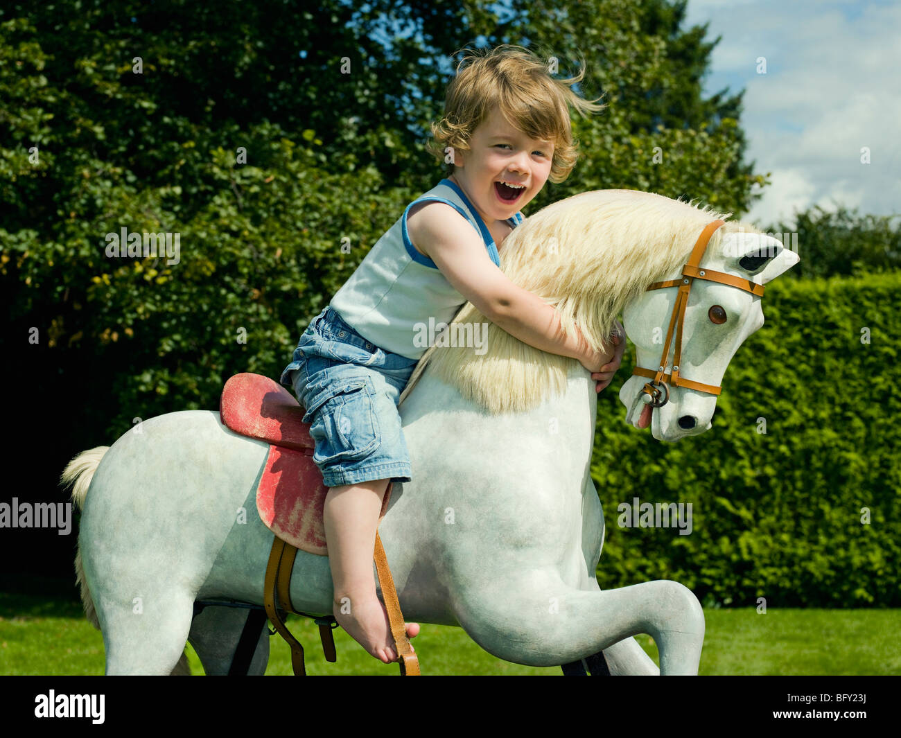 Un giovane ragazzo giocando su un cavallo a dondolo Foto Stock