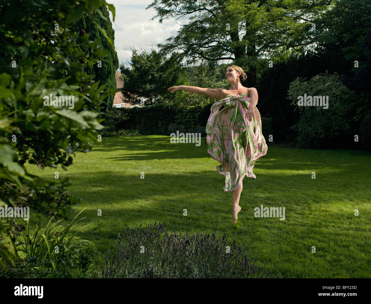 Una giovane donna dancing in un giardino Foto Stock