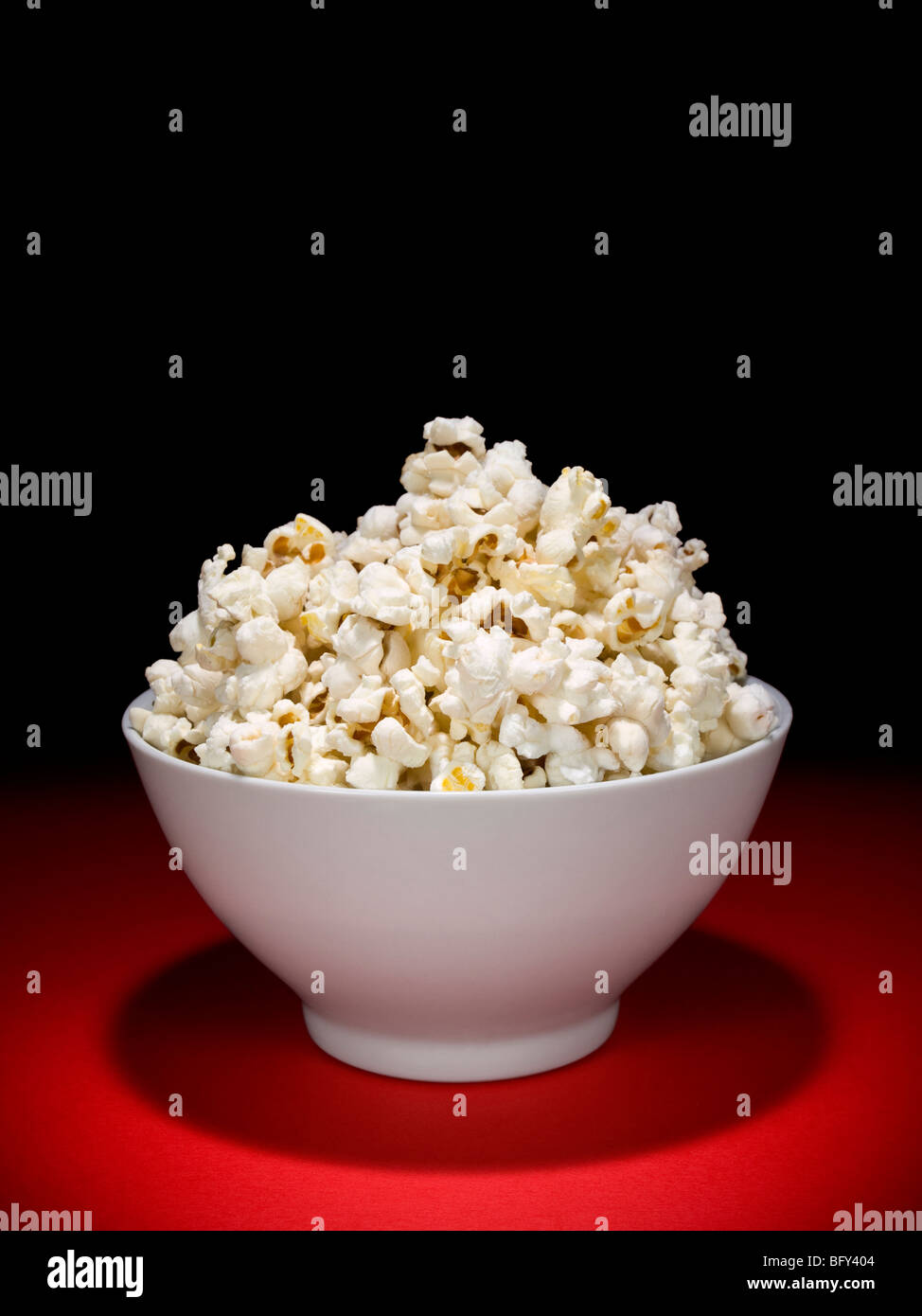Una ciotola piena di popcorn sotto i riflettori. Foto Stock
