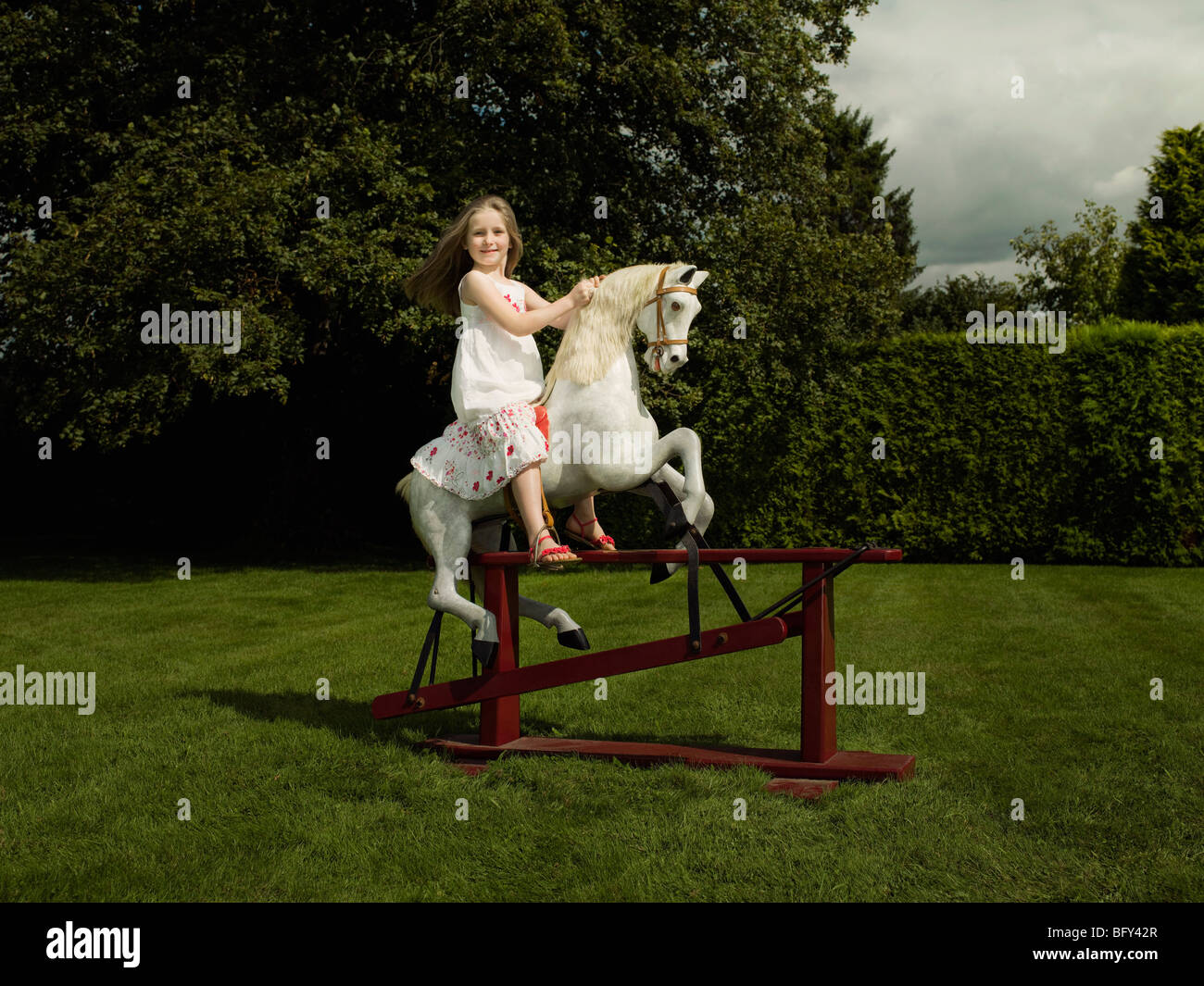 Una giovane ragazza su un cavallo a dondolo Foto Stock