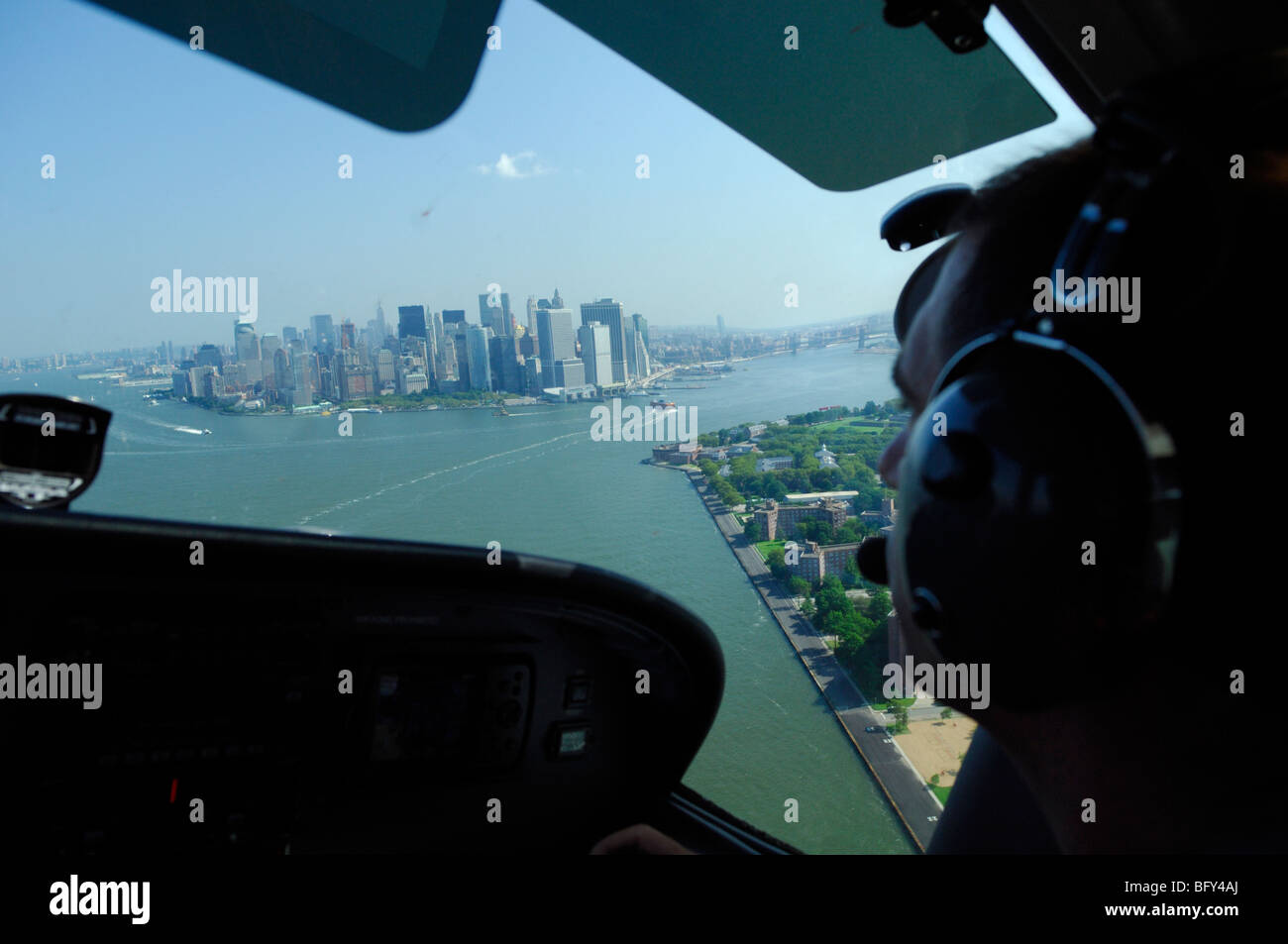 Un pilota di aereo leggero Cessna 172 sorvolano Governors Island, Manhattan e East River, New York City, Stati Uniti d'America Foto Stock