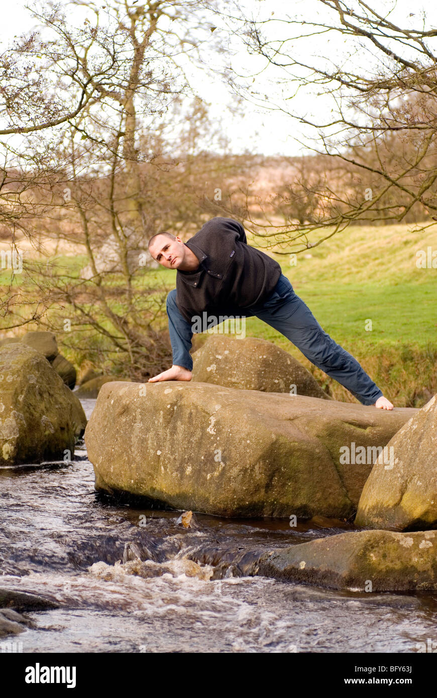 Doug Blane facendo Vinyasa yoga nel Parco Nazionale di Peak District, Derbyshire su gritstone rock Foto Stock