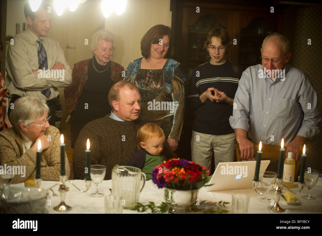 Famiglia riunita intorno al computer portatile a cena in famiglia Foto Stock