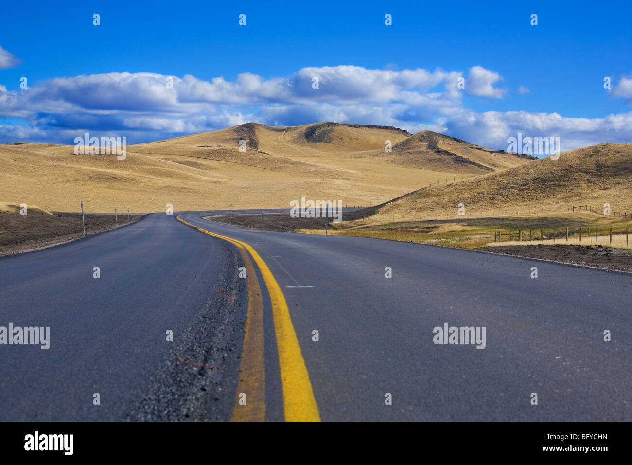 Autostrada corre verso il Prairie Butte, Montana, USA Foto Stock