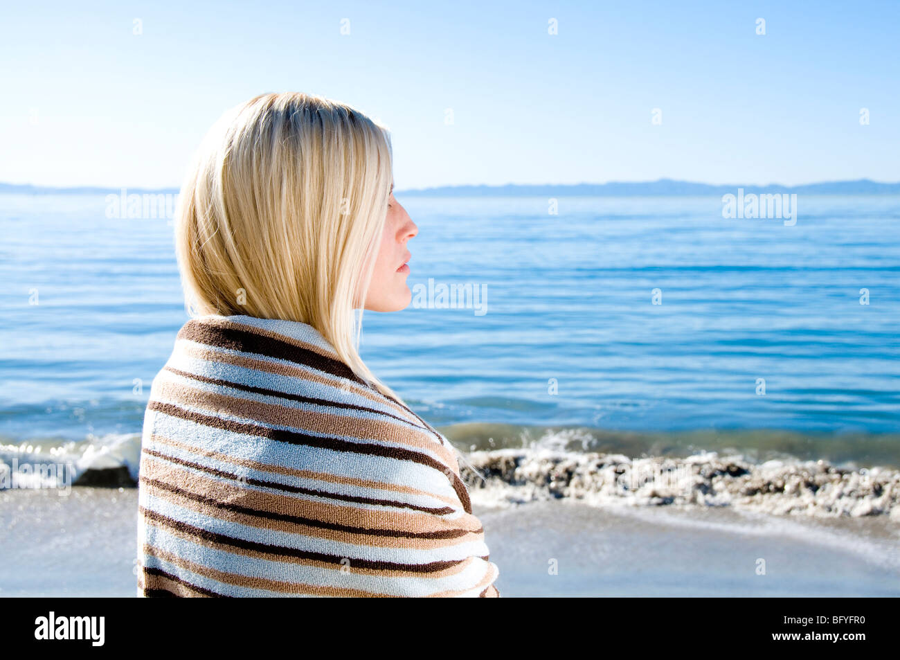 Donna avvolta in asciugamano guardando ocean Foto Stock