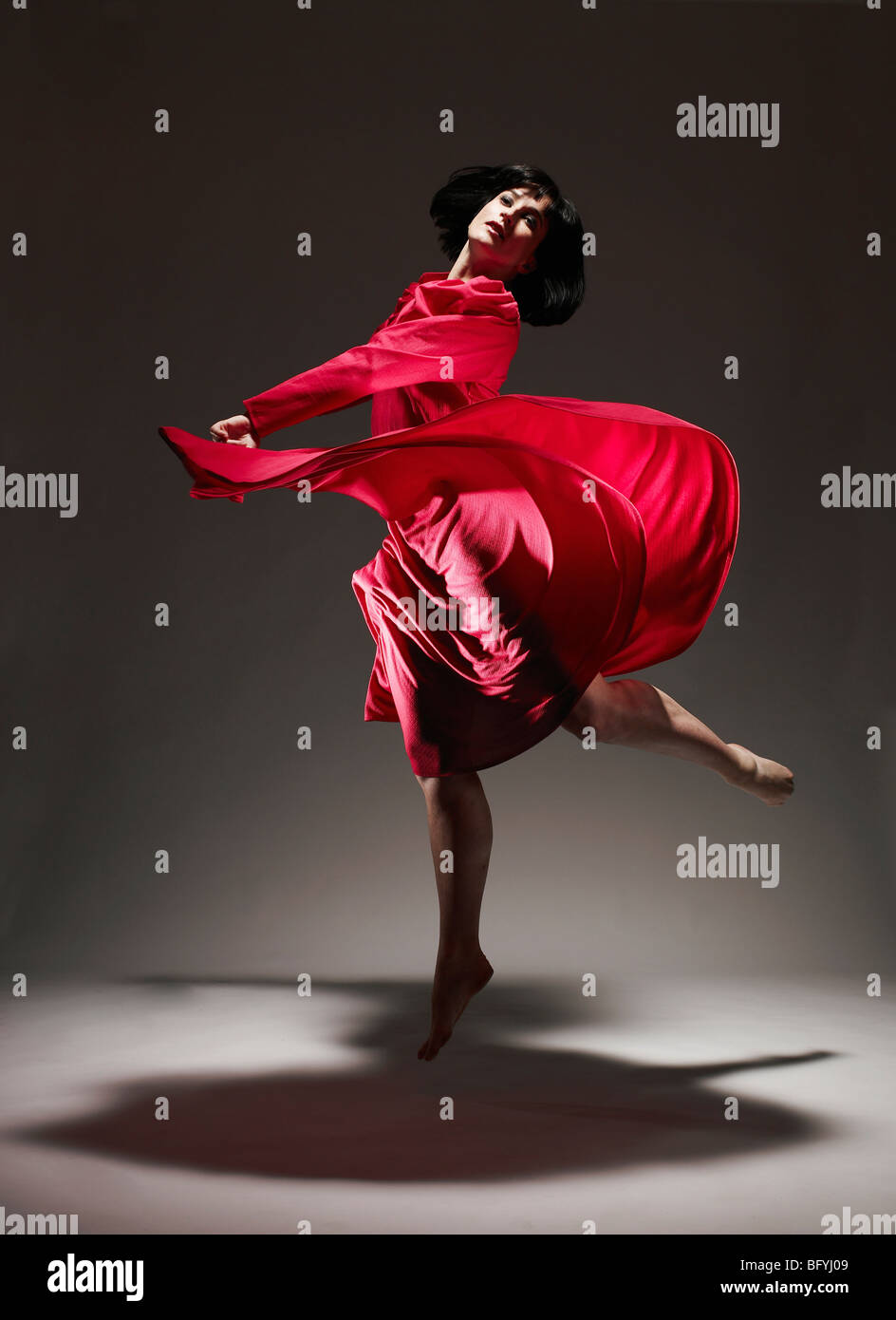 Donna in abito rosso ballando sotto luce Foto Stock