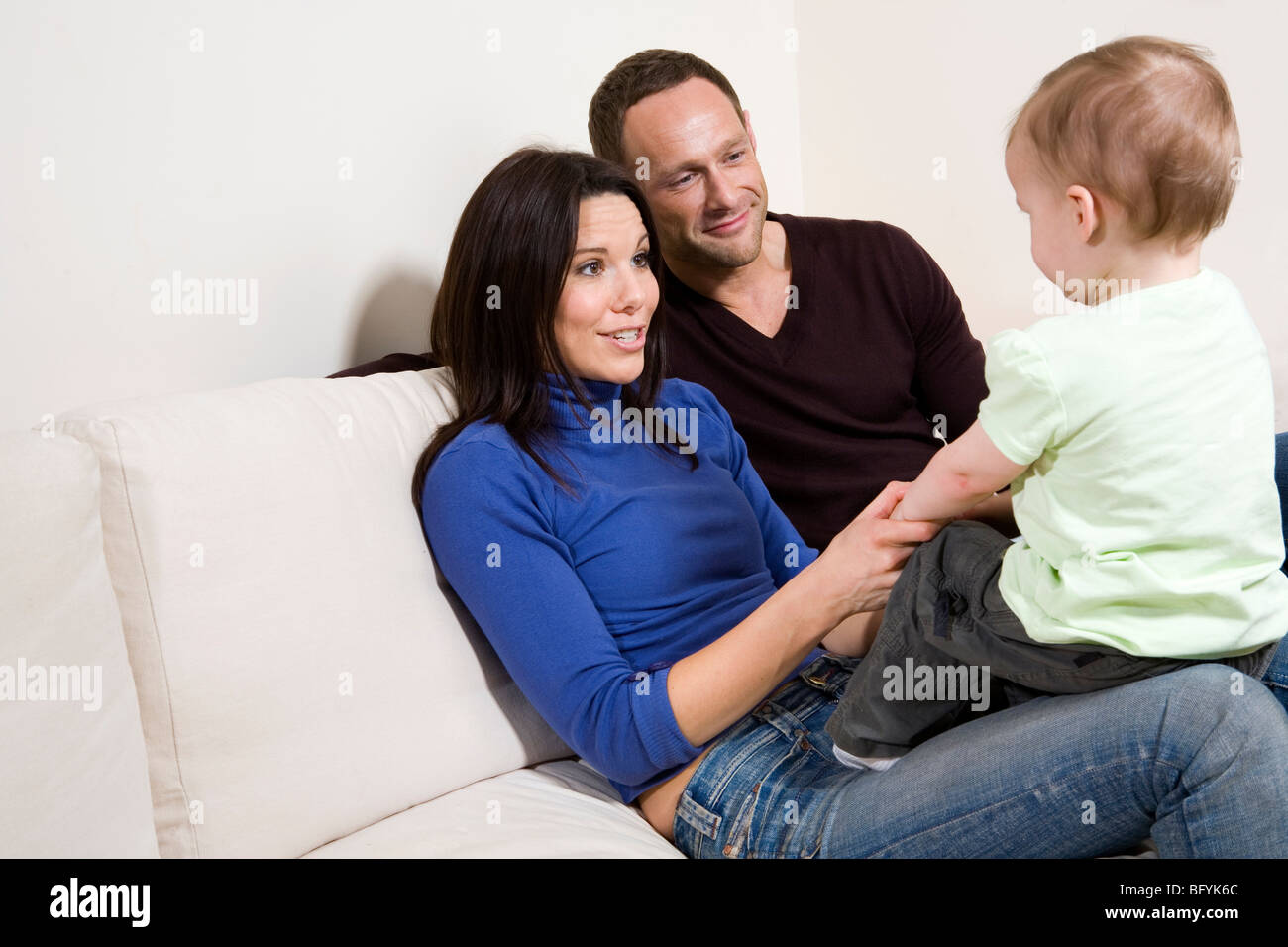 Paio di giocare con il loro bambino figlio sul divano Foto Stock