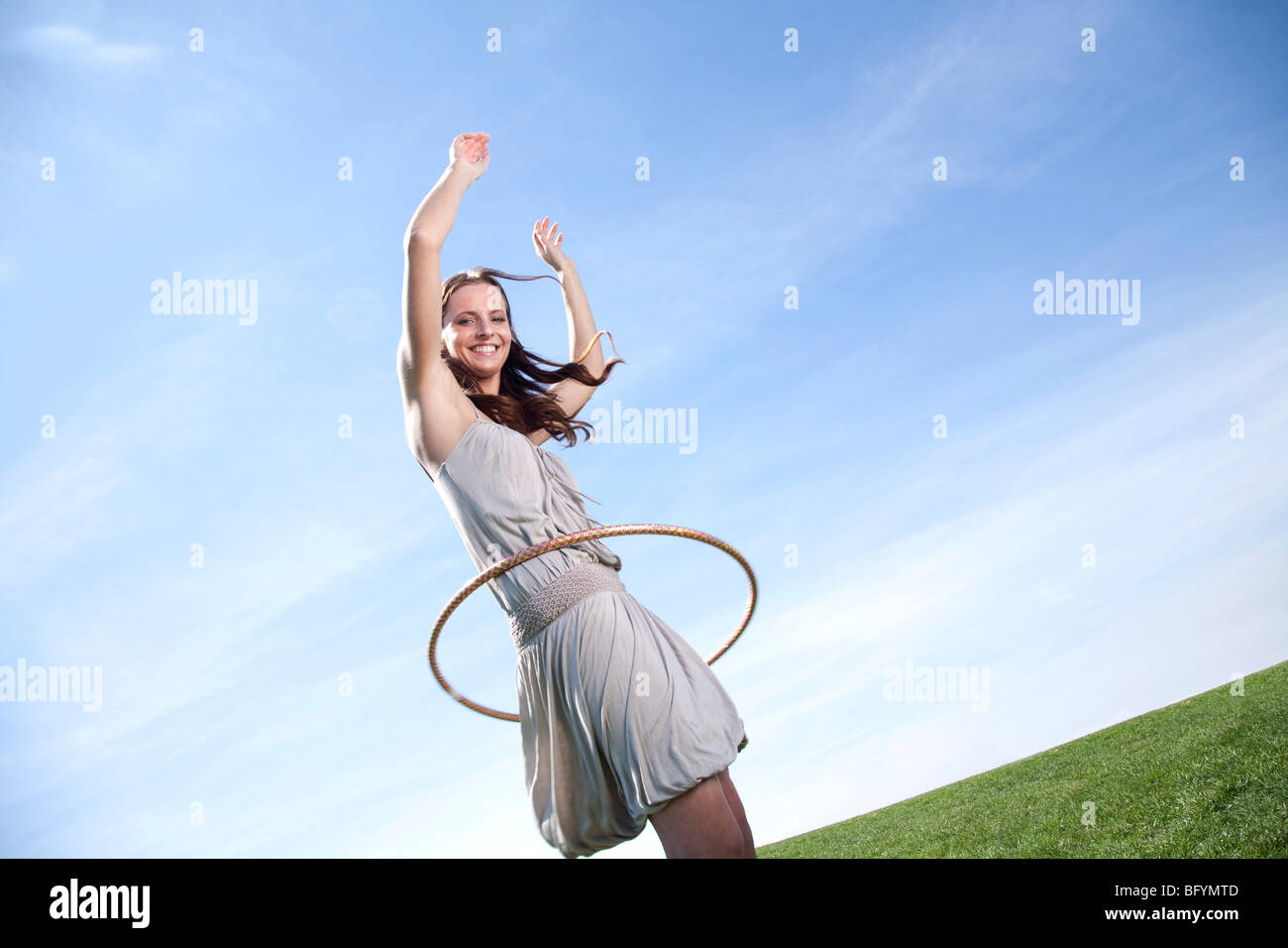 Giovane donna nel parco facendo hula hoop Foto Stock
