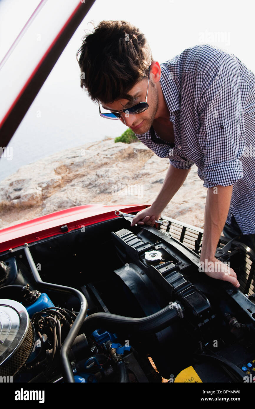 Uomo che guarda un auto a motore Foto Stock