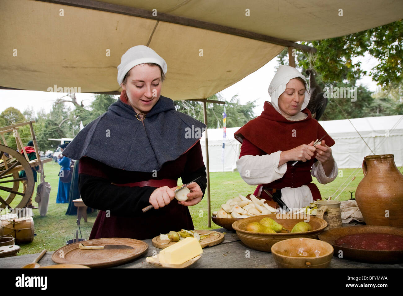Le donne, raffiguranti le classi inferiori del tardo XV secolo, preparare il cibo per un pasto medievale a storia viva fayre. Foto Stock