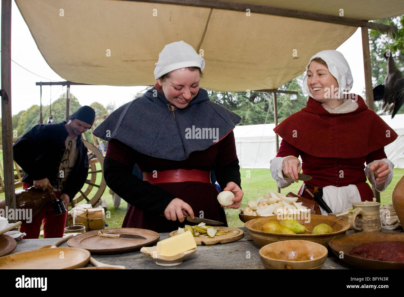 Le donne, raffiguranti le classi inferiori del tardo XV secolo, preparare il cibo per un pasto medievale a storia viva fayre. Foto Stock