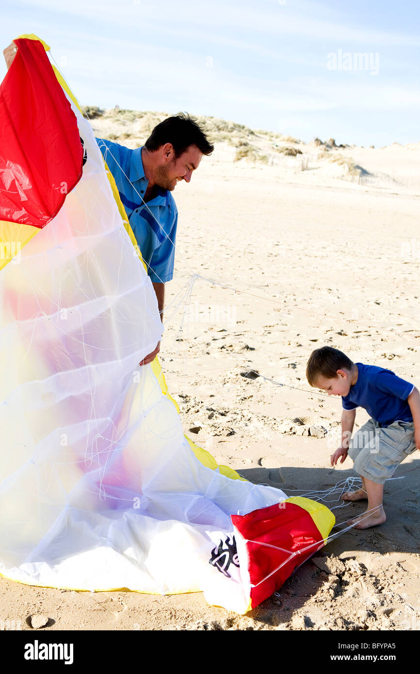 Un uomo e suo figlio si prepara a volare un aquilone sulla spiaggia Foto Stock