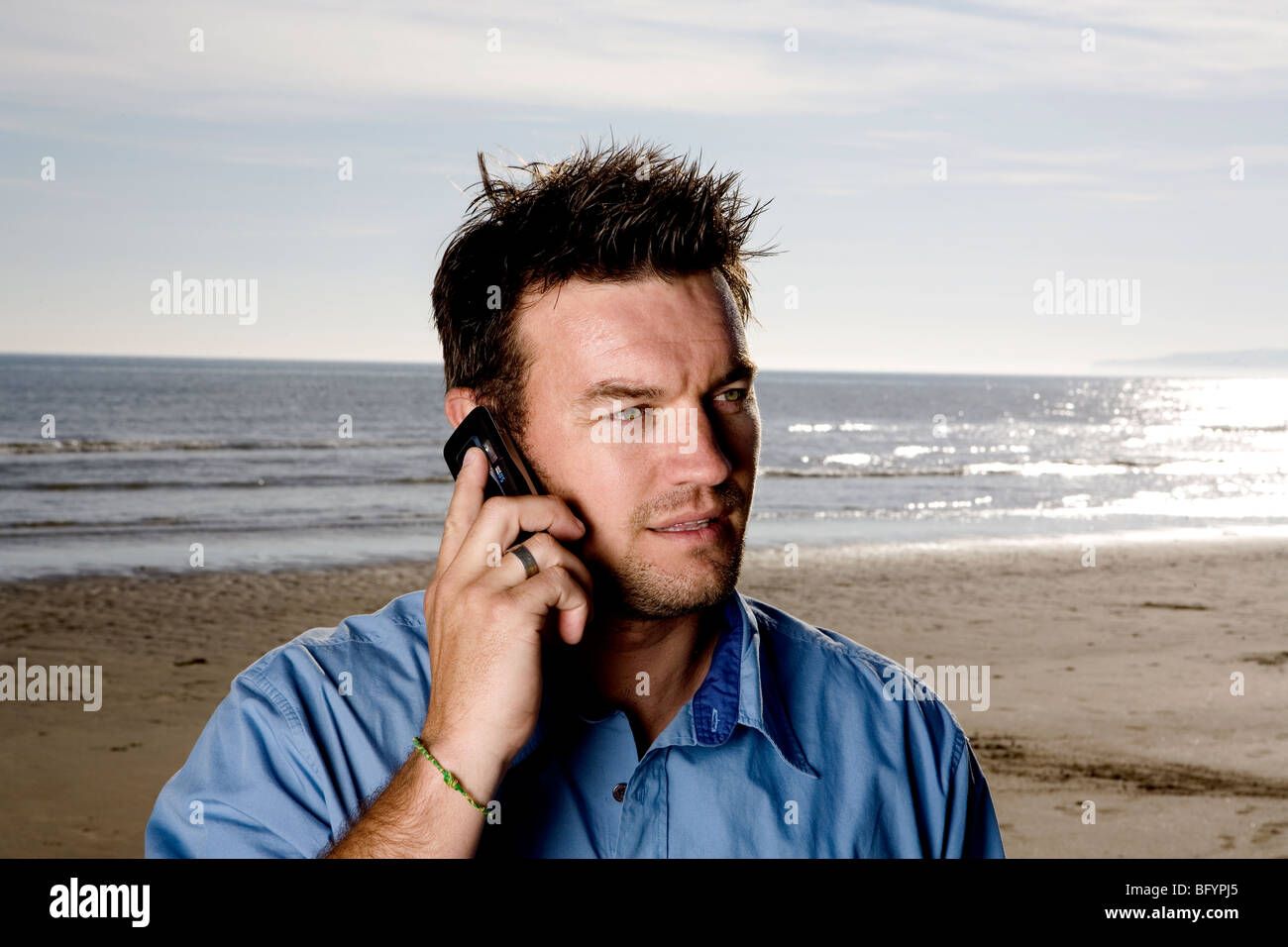 Un uomo con il suo cellulare in spiaggia, Foto Stock