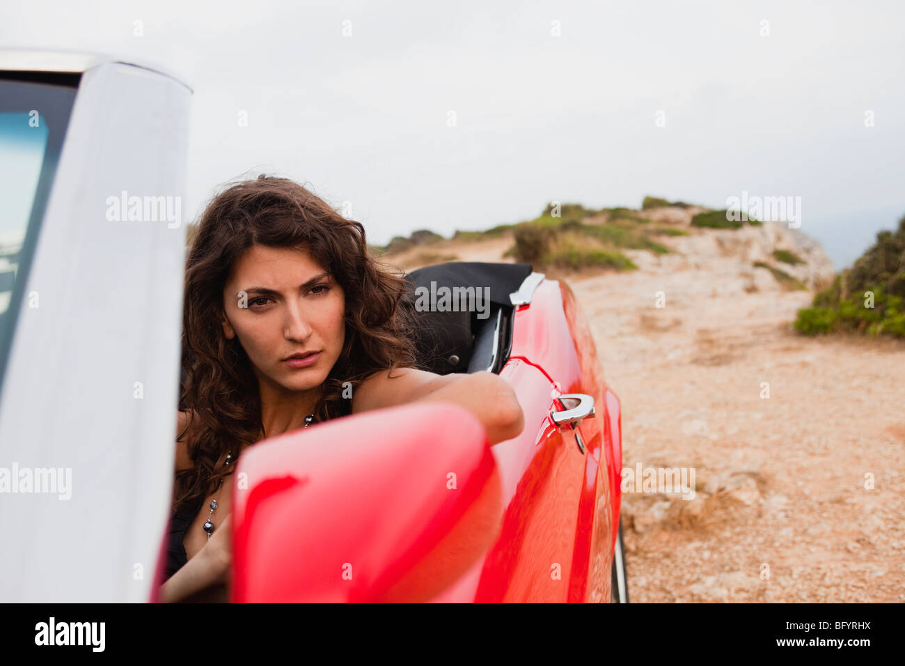 Donna seduta in un aperto superiormente e auto Foto Stock