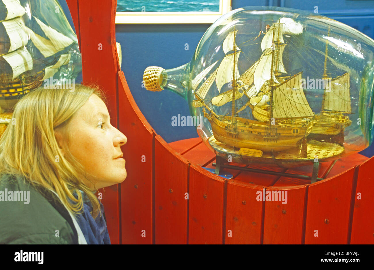 Una giovane donna sta guardando una bottiglia nave presso la bottiglia museo navale in Neuharlingersiel, East Friesland, Bassa Sassonia, Germania Foto Stock