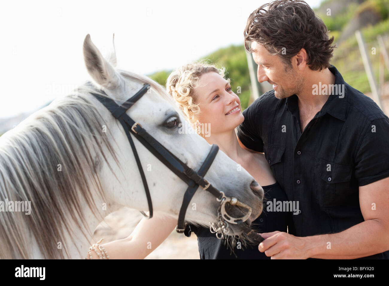 Coppia sorridente holding cavallo Foto Stock