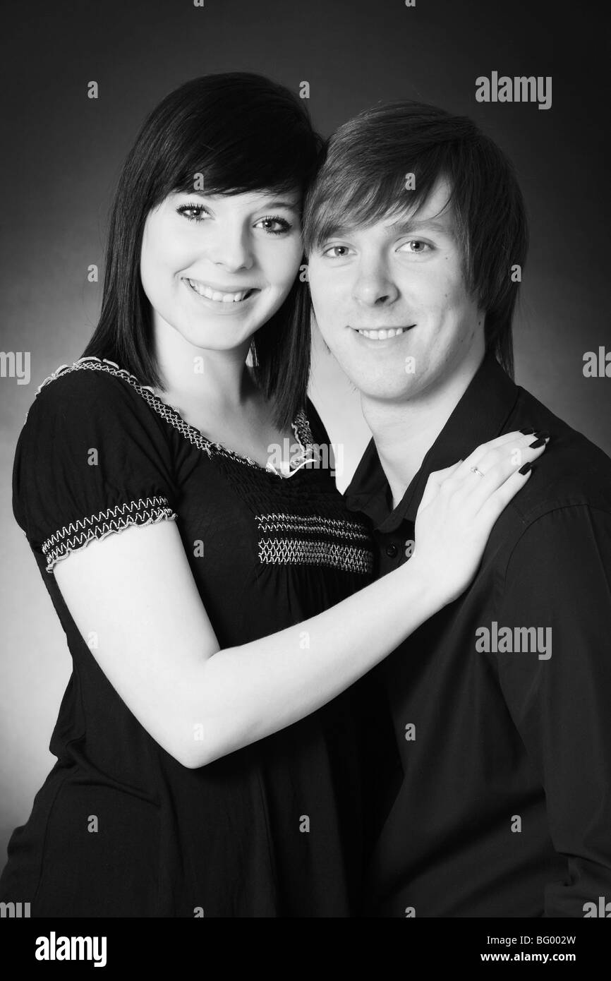 Una fotografia in bianco e nero di un attraente giovane coppia bianco abbracciando e sorridente in un studio fotografico impostazione Foto Stock