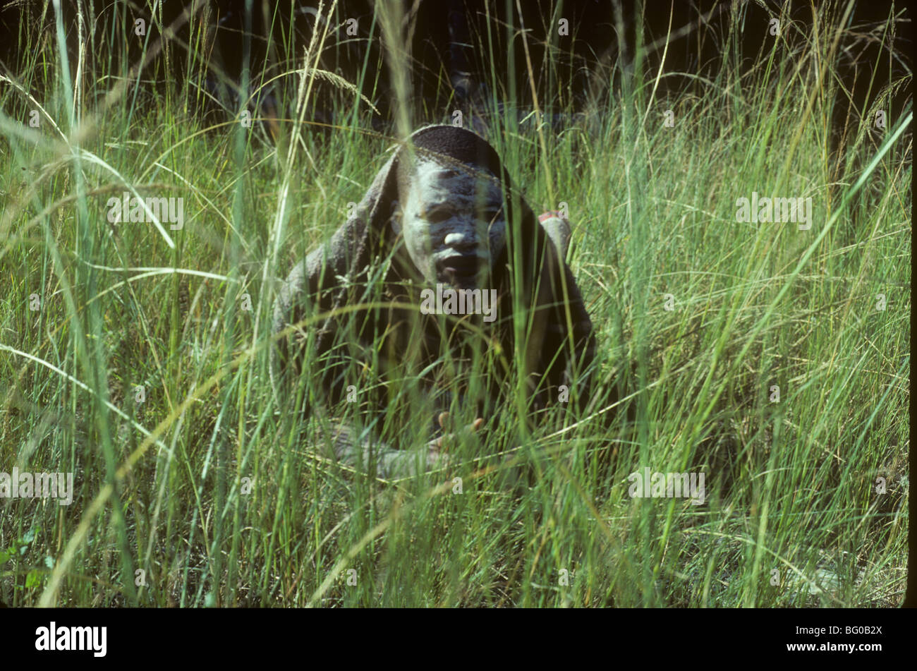 Un giovane uomo si appoggia nell'erba alta del Transkei (ora una parte del Sud Africa) dopo aver subito la circoncisione, il suo rito di passaggio a virilità Foto Stock