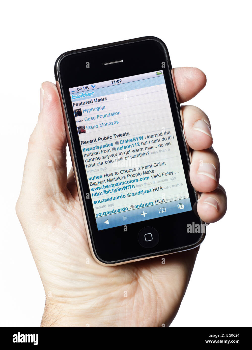 Mano maschile che tiene in mano un vecchio iPhone che mostra la cronologia pubblica di Twitter.com social media nel 2009 Foto Stock