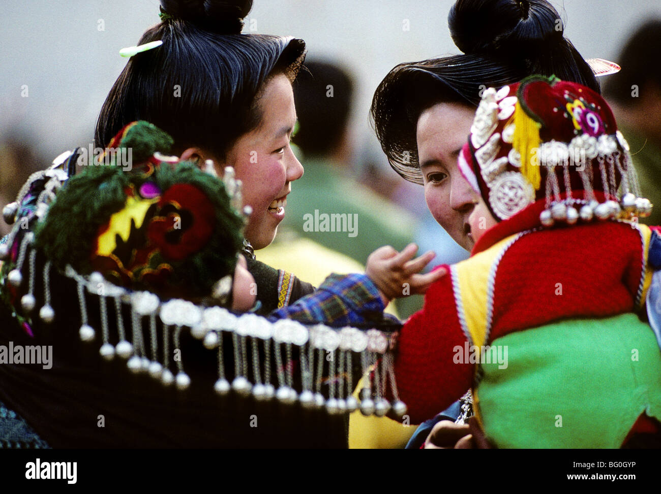 Due madri, membri di Miao minoranza etnica-uno dei più grandi minoranze etniche in Cina con circa 9 milioni di membri, portano i loro bimbi sulle loro spalle durante un festival di Guizhou, Cina Foto Stock