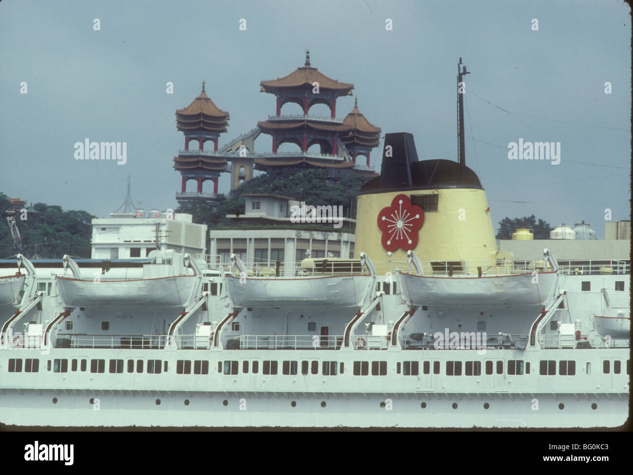 L'universo SS (ora scartati) con la prugna Fiore logo della Orient Overseas linea visualizzata sul suo stack è ancorata in Keelung, Taiwan con il padiglione nel Parco Chungcheng in background Foto Stock