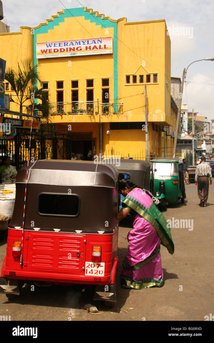 Una donna in un sari rosa ottiene in un tuk-tuk al di fuori della sala per matrimoni in Sri Lanka di capitale Colombo. Foto Stock