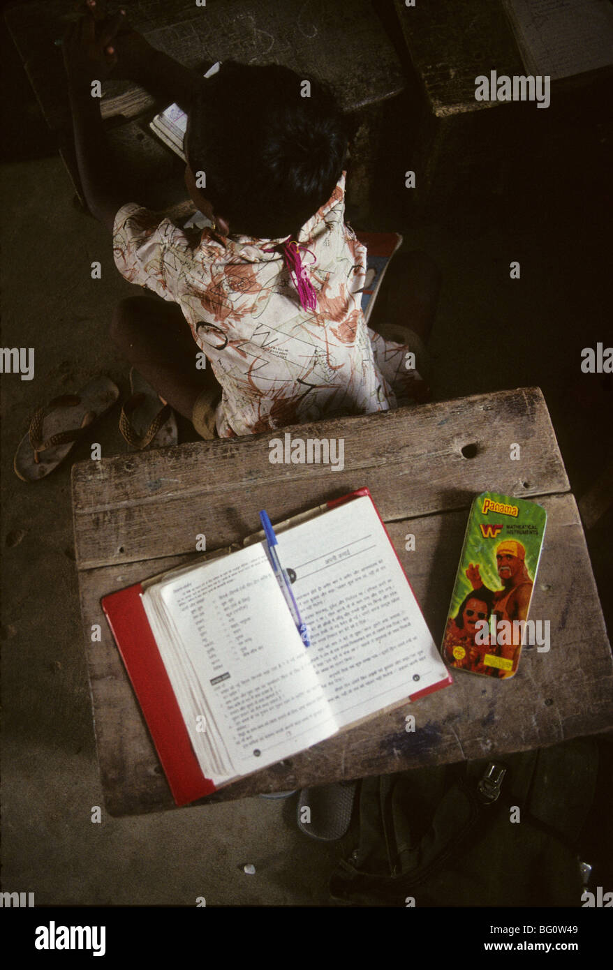 Un giovane scolaro alla sua scrivania con una scatola di Hulk Hogan matite dietro di lui in un piccolo villaggio vicino, Chennai, India Foto Stock Un giovane scolaro alla sua scrivania con una scatola di Hulk Hogan matite dietro di lui in un piccolo villaggio vicino, Chennai, India Foto Stock