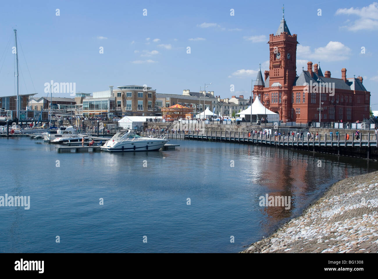 Vista della passeggiata lungo il Mermaid Quay con Edificio Pierhead in primo piano per la Baia di Cardiff, Cardiff Wales, Regno Unito Foto Stock