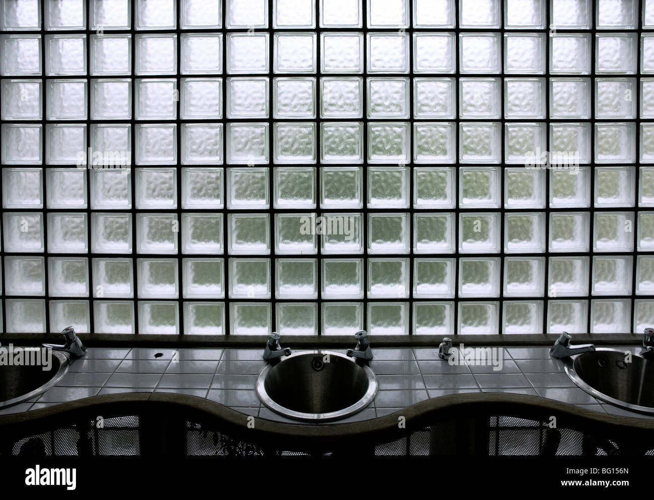 Mattoni in vetro e lavabo in un bagno pubblico, Abersoch Galles del nord Foto Stock