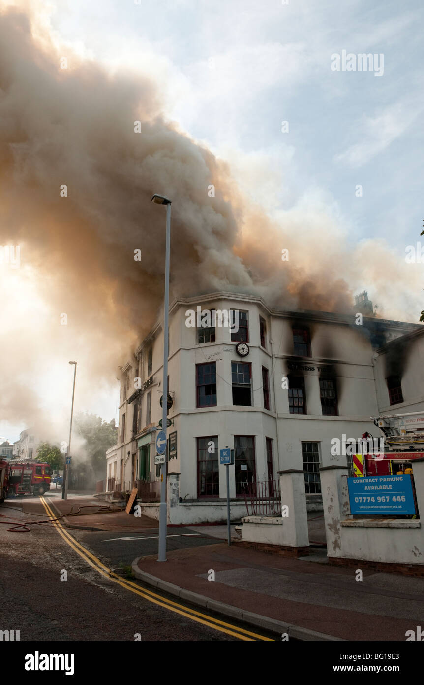 Pub hotel sul fuoco con emissione di fumo dal tetto Foto Stock