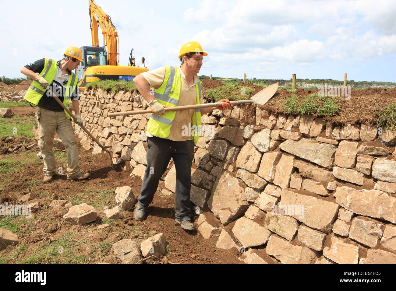 Operai costruendo un Cornish Hedge con grandi pietre è un muro costruito con pietra locale chiamato una siepe Foto Stock