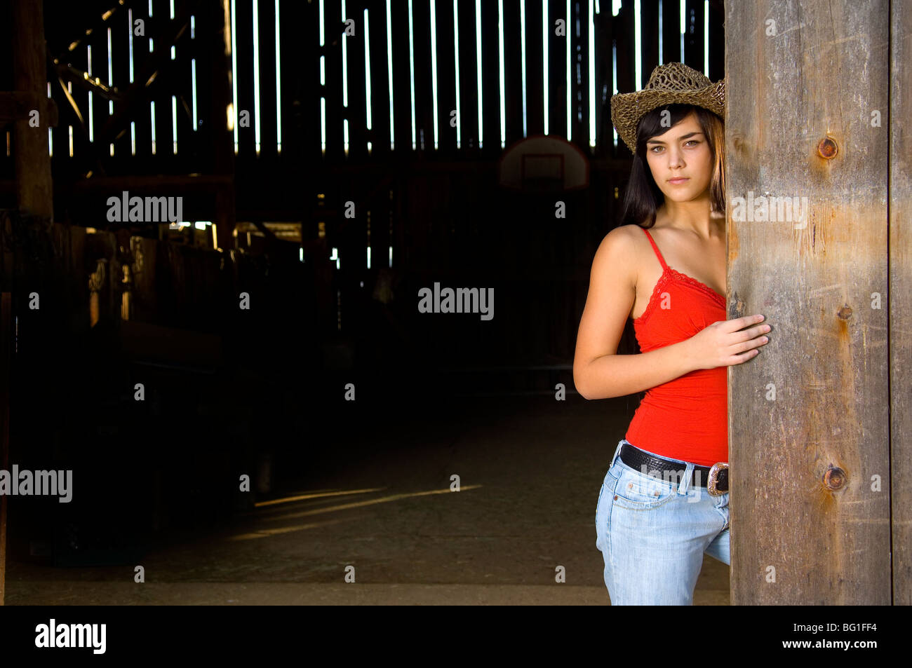 Cowgirl in fienile porta con il cappello e il serbatoio superiore Foto Stock