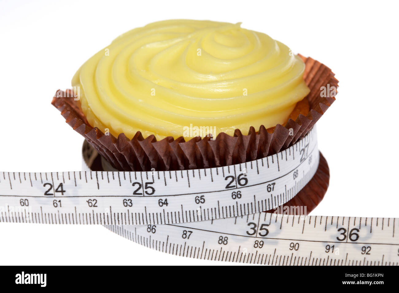 Giallo cupcake con glassa smerigliato schiacciato dal nastro di misurazione con misure metriche e imperiali Foto Stock