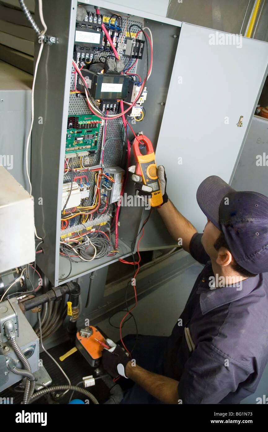 Lavoratore il test della tensione su un edifici di controllo ambientale casella. Foto Stock
