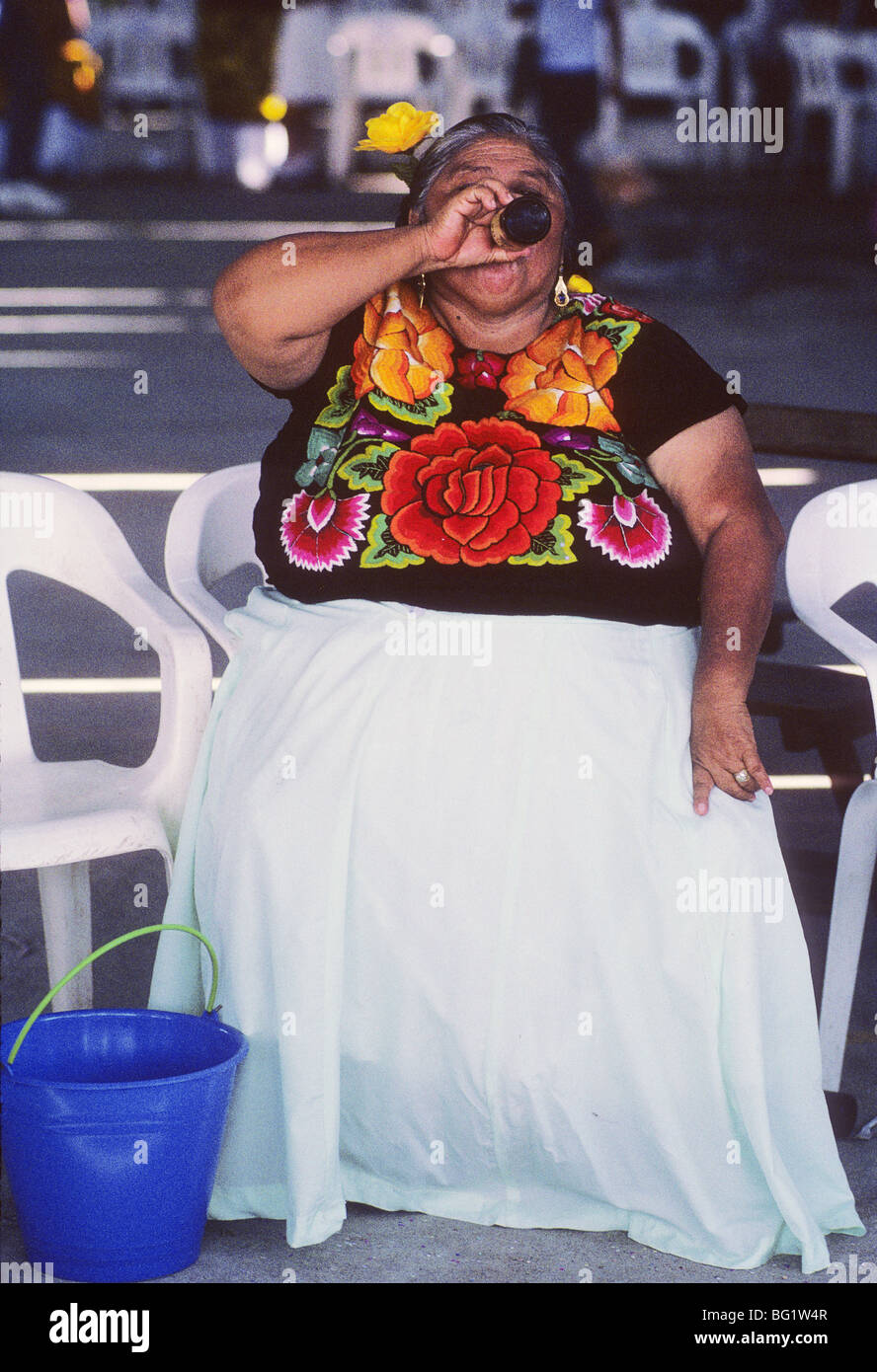 Una donna che beve birra da una bombola ad una fiesta in Tehuantepec, Messico le donne di questa città sono di estrazione zapoteco Foto Stock
