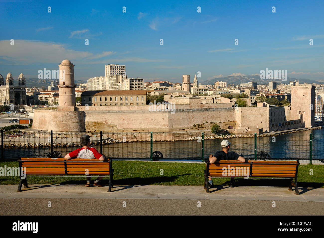 I visitatori o i turisti sulle panchine del Parco ammirano la vista sul Forte Saint Jean e Vieux Port dal Parco Palais du Pharo, Marsiglia o Marsiglia, Francia Foto Stock