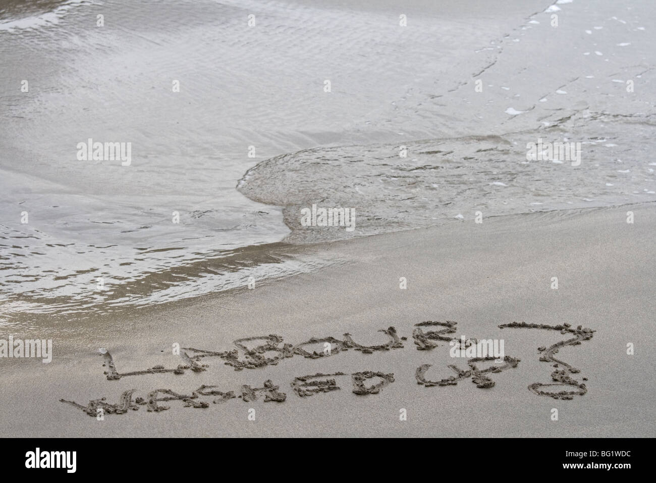 Lavoro lavato su scritto nella sabbia con una marea di svolta. Simbolico Foto Stock