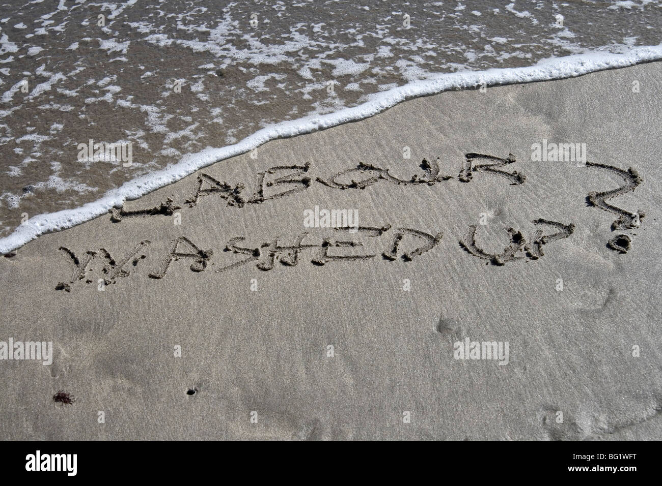 Lavoro lavato? Scritto nella sabbia con la marea che gira. Foto Stock