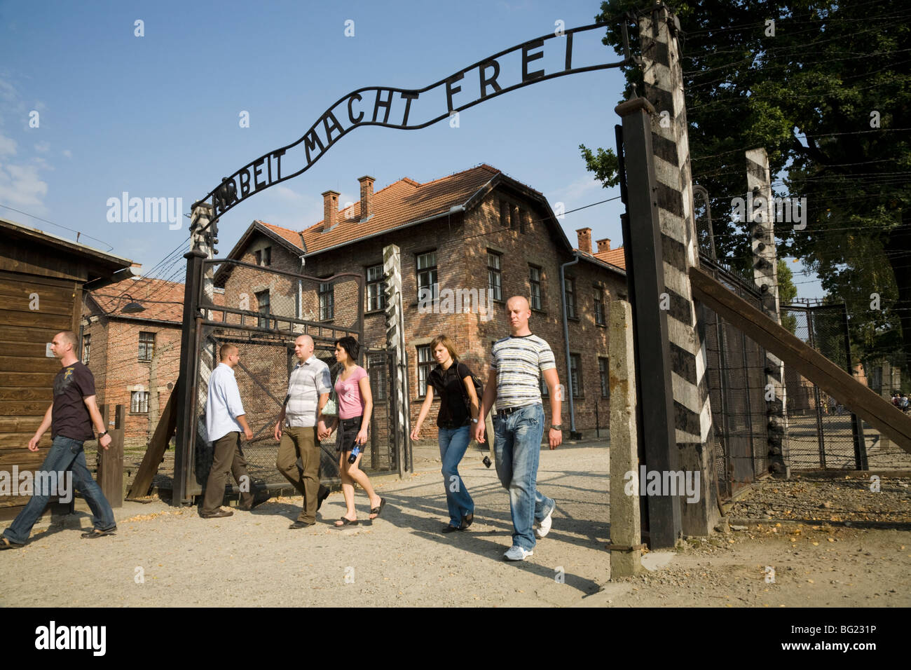 I turisti all'ingresso principale - con vero Arbeit macht frei slogan sopra le porte - ad Auschwitz Nazi camp in Oświęcim, Polonia Foto Stock